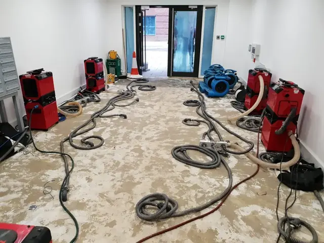 Dehumidifiers and air movers lined up to dry a long wet room in Vacaville