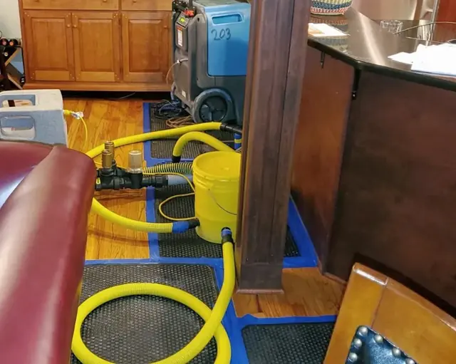 Floor drying mats and hoses pulling water out of a wet hardwood floor