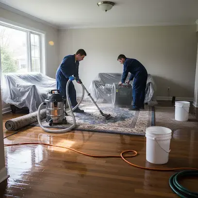 Two technicians extracting water from a rug on a wet wood floor in Vacaville