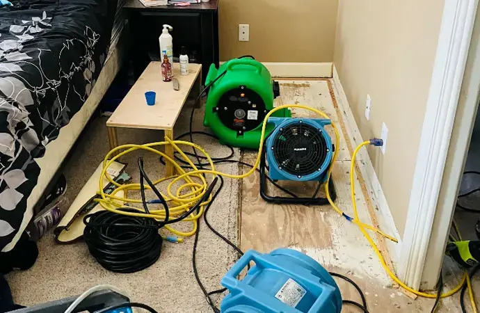 Air movers and a dehumidifier running over a wet bedroom floor in Vacaville